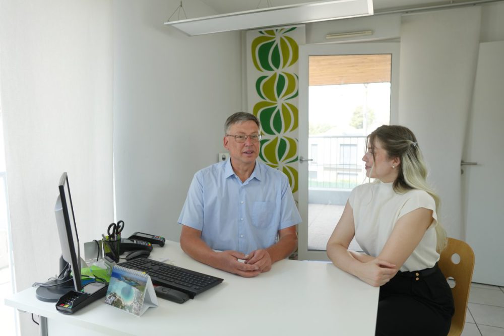 Heller Behandlungsraum in einer Praxis mit Gesprächssituation zwischen Arzt und Patientin