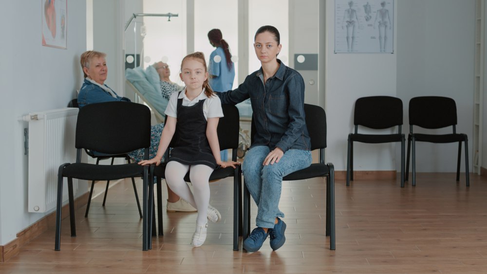 Wartebereich einer Arztpraxis mit Patientinnen und einer Ärztin im Hintergrund