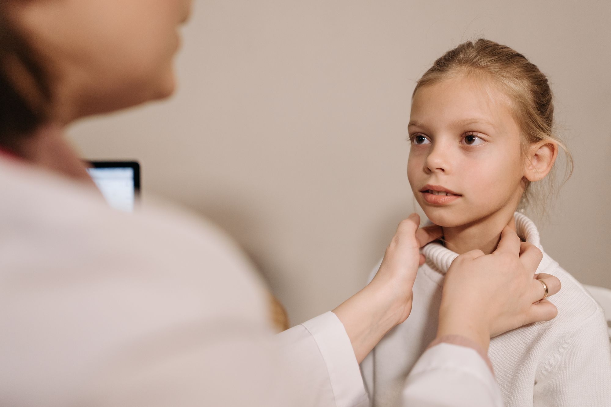 Ärztin tastet bei einem Mädchen die Schilddrüse am Hals ab