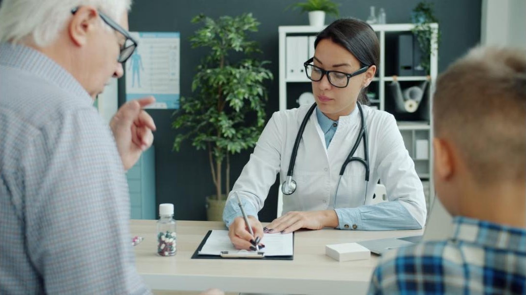 Hausärztin im Gespräch mit einem Patienten am Schreibtisch
