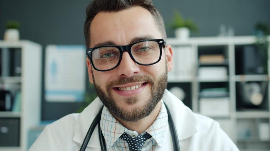 Arzt mit Brille und Stethoskop im Behandlungszimmer