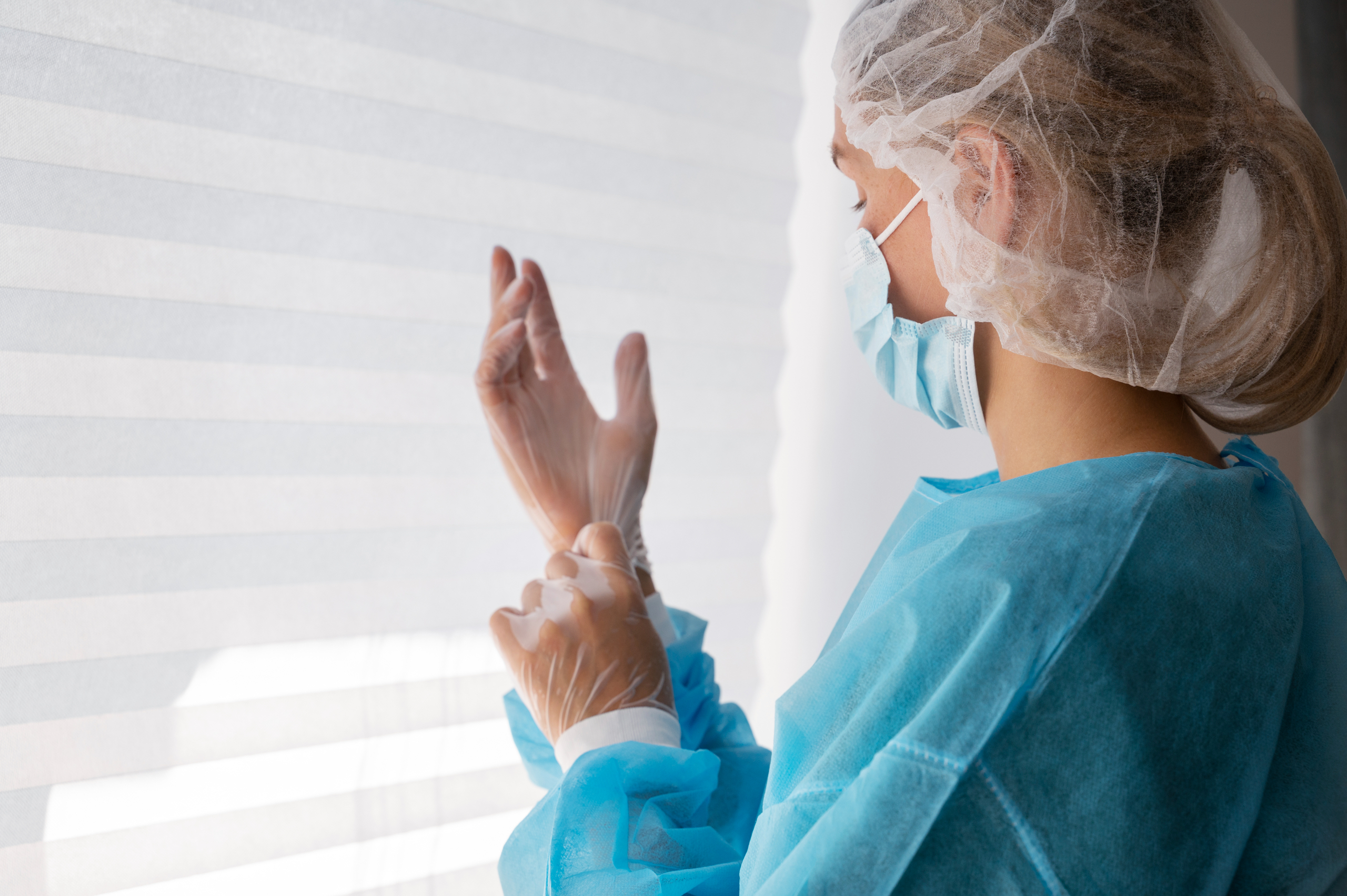 &Auml;rztin zieht vor einem Eingriff Handschuhe an